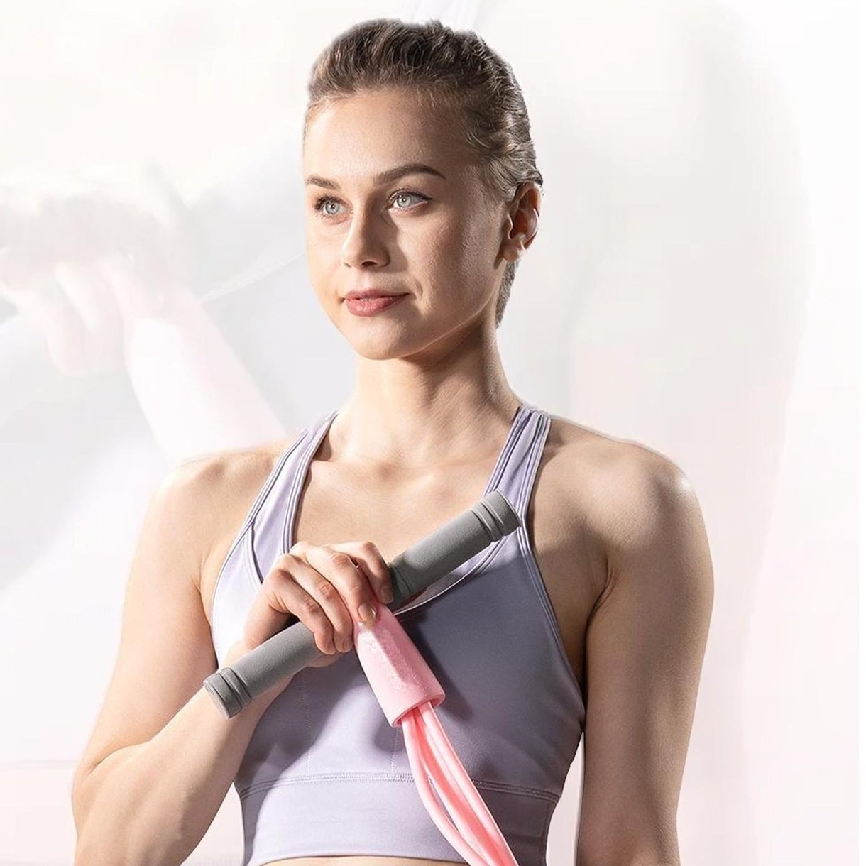 A woman holding the pink Pomence Pedal Resistance Band by its gray foam handles