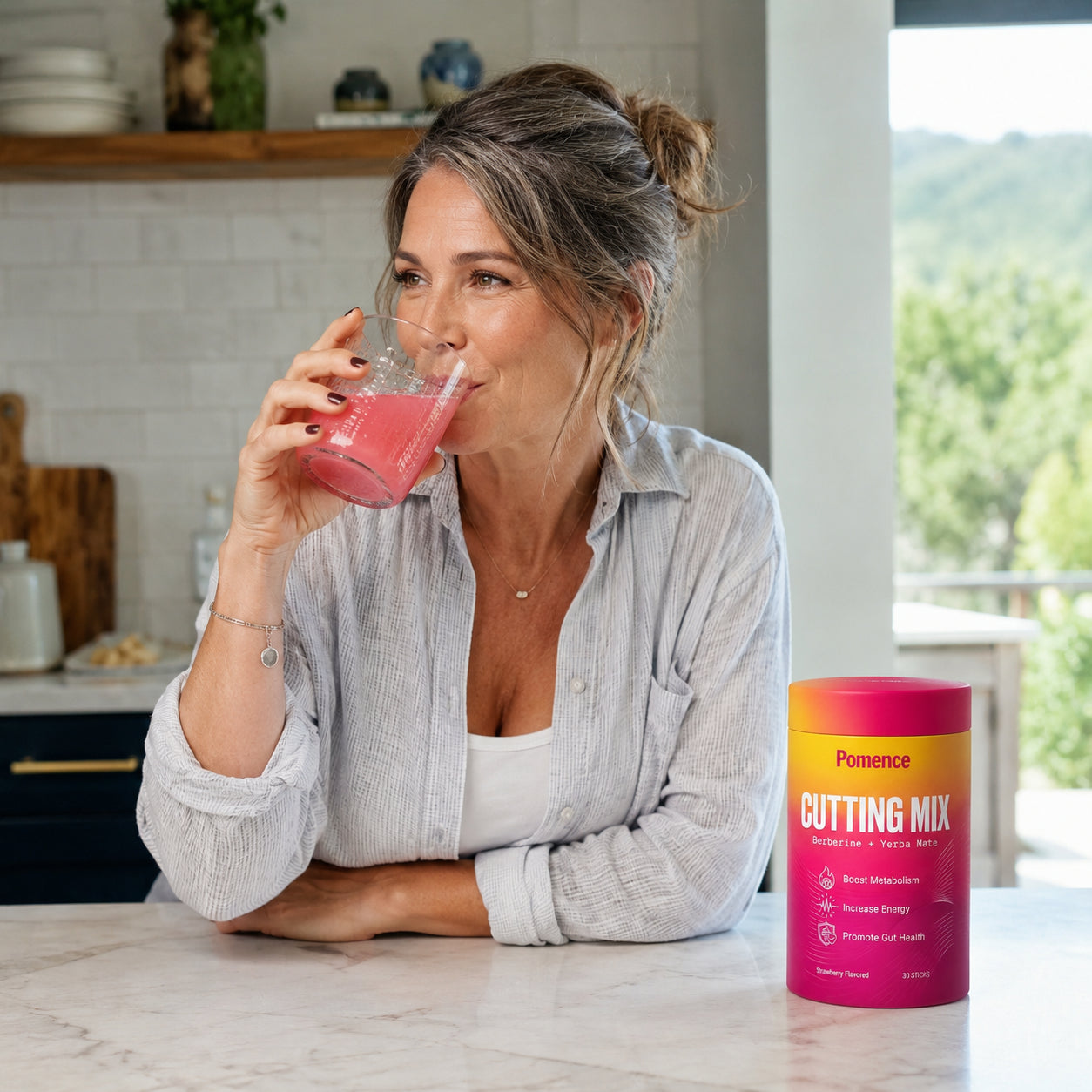 Woman happily drinking her Pomence Cutting Mix at the kitchen counter