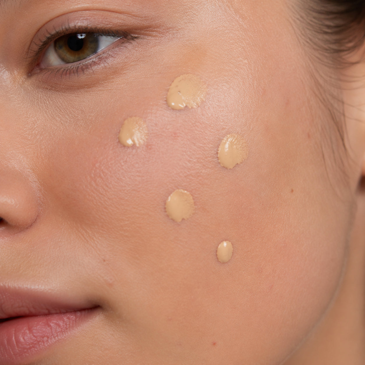 Small dots of foundation applied to a woman's cheek before blending
