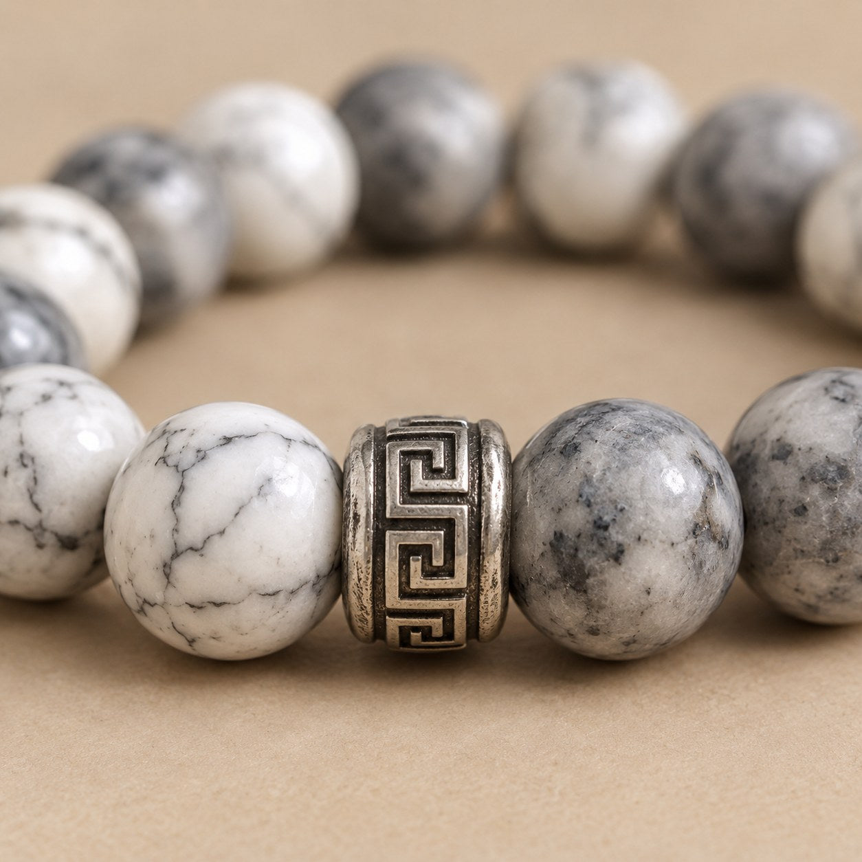 Close macro of a Greek key carved barrel spacer between two beads on the Pomence Pixiu Wealth Bracelet