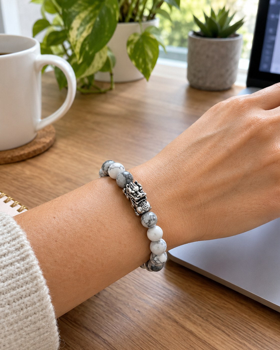 A woman's wrist wearing the Pomence Pixiu Wealth Bracelet as she works at a laptop in a home office