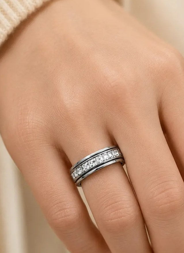 Steel spinner ring worn on a hand against a cream knit sleeve