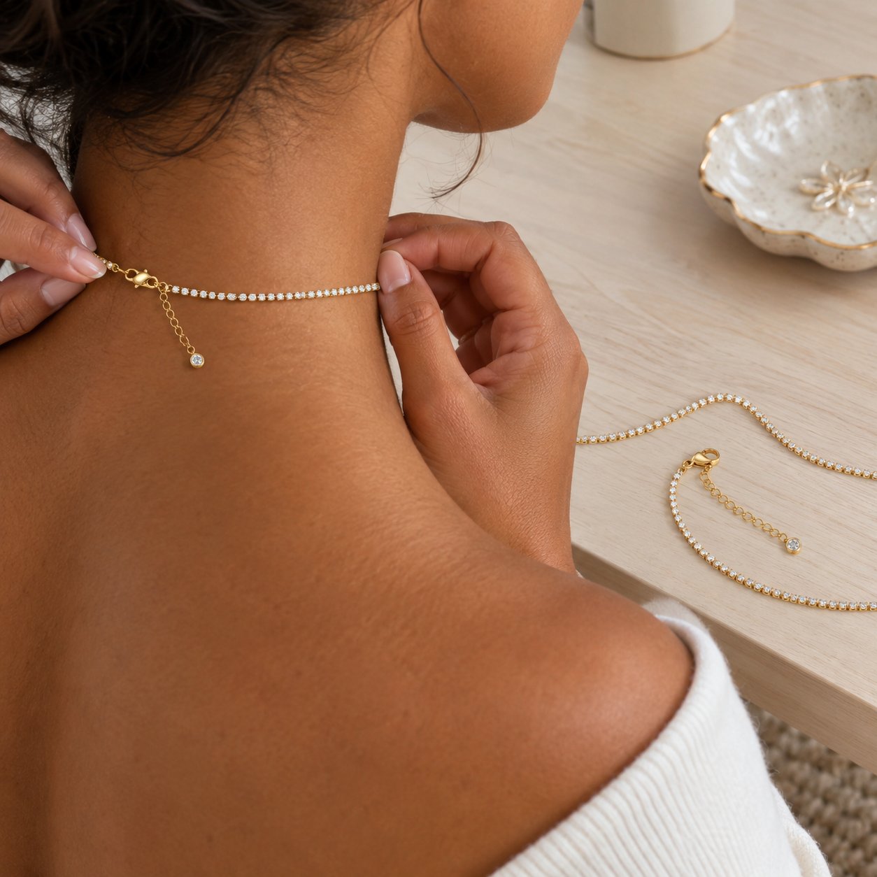 The Pomence Tennis Necklace at a vanity, a second view laid flat so the lobster clasp and 2 inch extender are visible